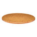 A close-up of a Perfect Tables 24" Outdoor Round Knotty Pine Table Top on a wooden table.