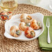 A plate of snails with an Acopa snail fork and a knife on a table.
