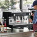 A woman working on a Gaggia Vetro Black espresso machine on a counter.