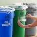 A woman putting a Lavex label on a green trash can.