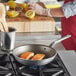 A person cooking two pieces of salmon in a Vollrath aluminum non-stick fry pan.