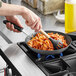 A person cooking pasta in a Vollrath carbon steel non-stick fry pan.