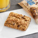 A Betty Crocker chocolate chip oatmeal bar on a napkin next to a glass of orange juice.