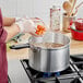 A person using a Vollrath Wear-Ever sauce pan to cook carrots.