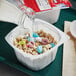 A close-up of a Lucky Charms single-serve bowl of cereal with milk pouring into it.