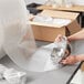A woman wrapping a silver bowl with Lavex Small Bubble Roll.