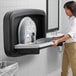 A woman using a Koala Kare matte black stainless steel baby changing station.