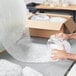 A person's hands reaching into a clear jar of Lavex bubble wrap.