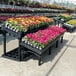 A group of colorful flowers on a black plastic grid tilt-top platform display.