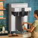 A woman pouring coffee into a Fetco coffee maker.