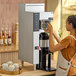 A woman using a Fetco CBS-1251 Plus Series automatic coffee machine on a counter in a coffee shop.