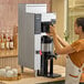 A person using a Fetco CBS-1251 Plus automatic coffee machine in a coffee shop.