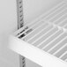A white shelf with metal pilasters on it.