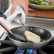 A piece of meat being cooked in a Vigor SS3 Series stainless steel non-stick frying pan.