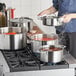 A woman cooking food in a Vigor stainless steel stock pot on a stove.