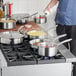 A person cooking soup in a Vigor stainless steel saucier pan on a stove.