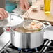 A person cooking shrimp in a Vigor stainless steel stock pot.