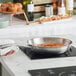 A woman cooking with a Vigor SS3 Series stainless steel fry pan on a professional counter.