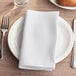 A white napkin on a plate with a fork and knife.