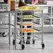 A woman uses a Regency wire rack with trays of fruit.