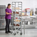 A woman standing next to a metal rack for platters.