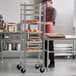 A man standing next to a Regency unassembled sheet pan rack filled with pastries.