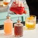 A bartender using a Barfly glass bottle to pour liquid into a cocktail.