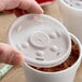 A hand holding a Dart translucent plastic lid on a plastic cup.