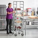 A woman in a purple shirt standing in a professional kitchen with a Regency platter rack.