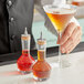 A bartender holding two Barfly glass bottles filled with liquid.