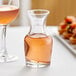 A Libbey carafe filled with pink liquid on a table with food.