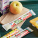 A tray with Go-GURT, a yellow apple, and juice on a table.