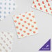 A group of white Choice interfolded bakery tissue sheets with customizable orange and white designs.