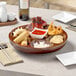 A Town carved wooden Pu Pu platter with food on it on a table.
