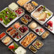 A tray of food with rectangular bowls of olives, cheese, and fruit on a table.