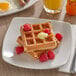 A plate of Krusteaz whole grain waffles with raspberries and syrup.