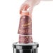 A hand using a San Jamar EZ-Fit cup dispenser to get a coffee cup.