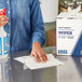A person using a Lavex industrial wiper to clean a counter.