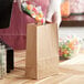A person in gloves pouring candy into a ChoiceHD Natural Kraft bag on a wood surface.