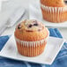 An Otis Spunkmeyer Wild Blueberry Muffin in a white wrapper on a plate with a fork.