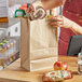 A woman putting a bag of food in a Choice natural Kraft paper bag.