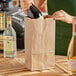 A person opening a Choice heavy-duty paper bag with a bottle of wine inside.