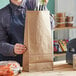 A woman holding a brown ChoiceHD paper bag of food in an organic food store.