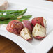 A CAC rectangular porcelain platter with green beans, potatoes, and meat on a wood table.