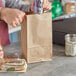 A person putting food in a ChoiceHD natural kraft paper bag.