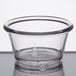 A clear plastic ramekin on a white surface.