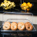 A Cal-Mil shallow clear bakery tray holding bagels and fruit on a counter.