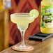 A glass of Zing Zang Margarita Mix with a lime wedge on the rim.