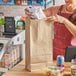 A woman putting groceries in a Choice brown paper bag.