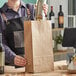 A hand holding a ChoiceHD Shorty natural kraft bag on a wood surface.